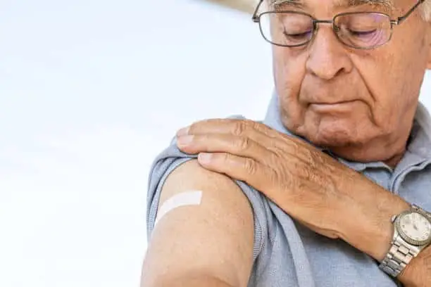Senior man is looking at his arm after vaccination.